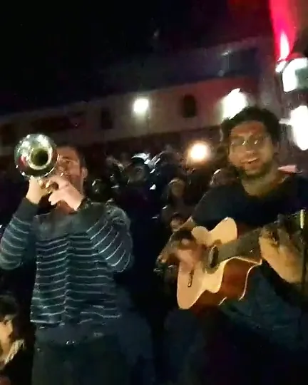 מעריצים מנגנים בחצוצרה ובגיטרה באולם, לפני ההקרנה של אנדגיים